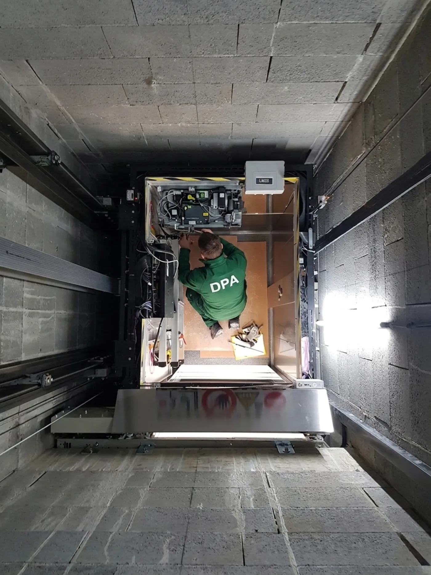 Contrôle depuis le toit de cabine d'un ascenseur à Paris pendant l'entretien